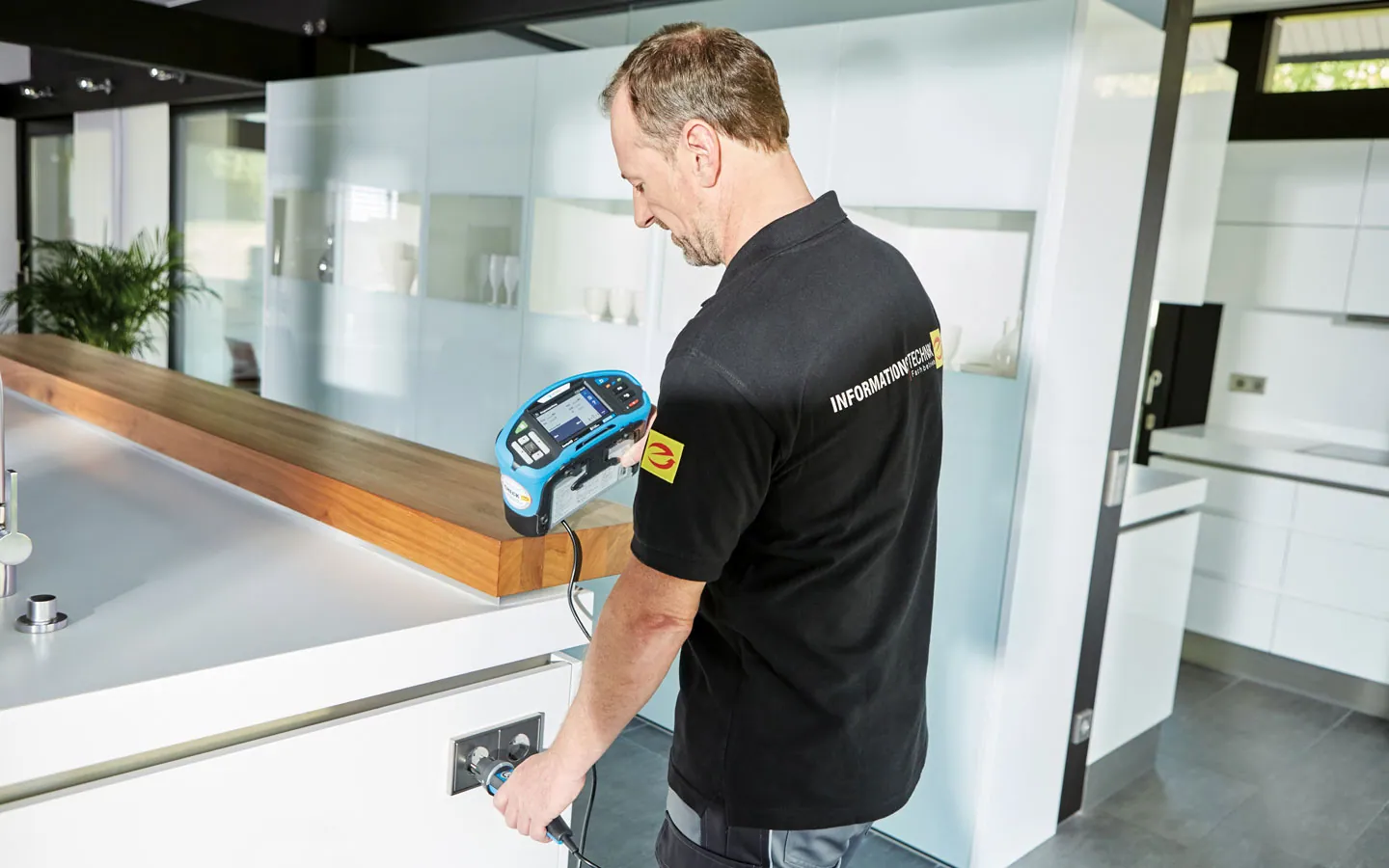 E-CHECK - Mitarbeiter prüft die Steckdosen in der Küche · Elektro Busch GmbH