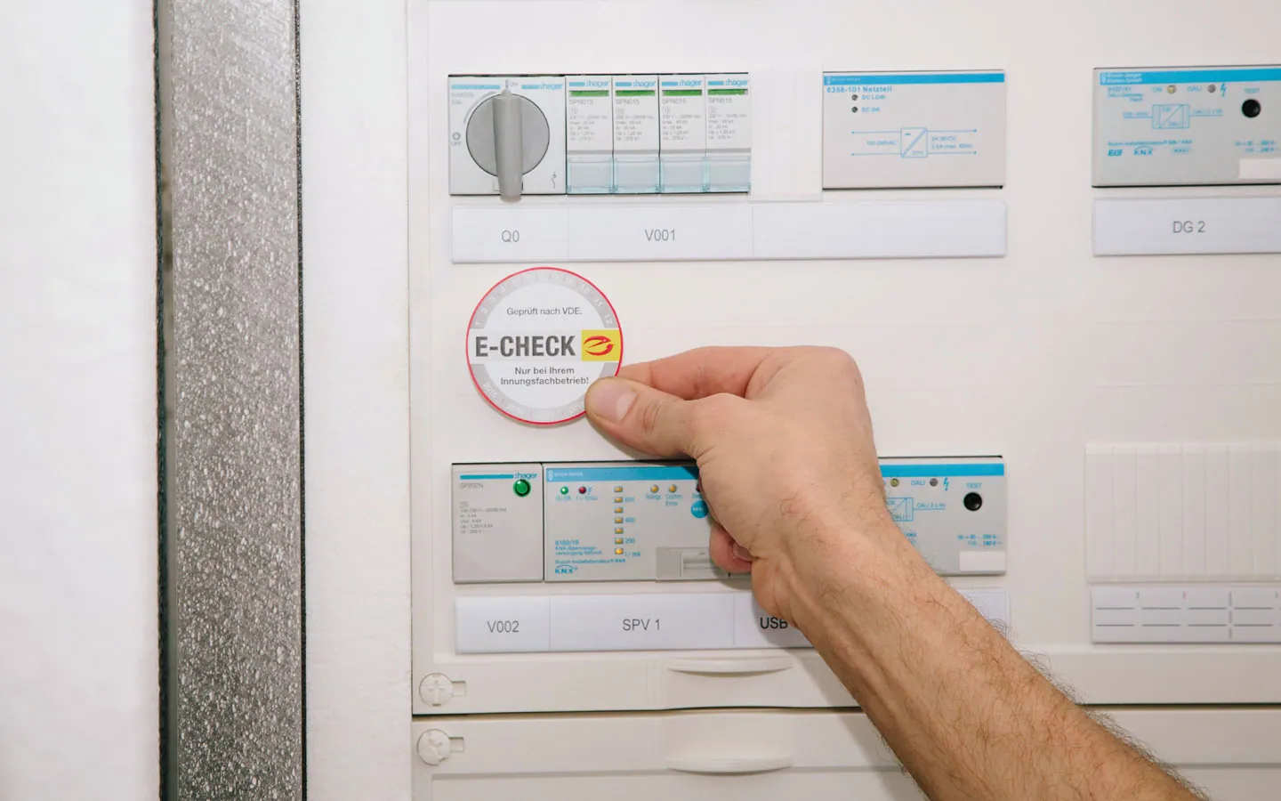 E-CHECK - Mitarbeiter klebt in der Verteilung die E-CHECK Plakette an · Elektro Busch GmbH