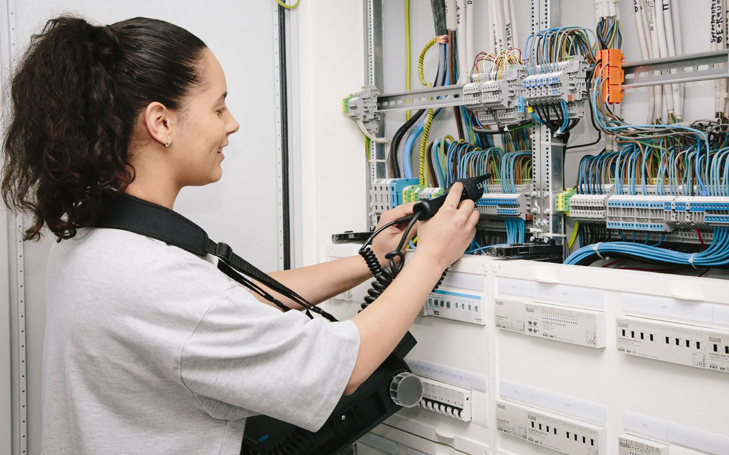 E-CHECK - Mitarbeiterin prüft im Schaltschrank mit einem Meßgerät · Elektro Busch GmbH